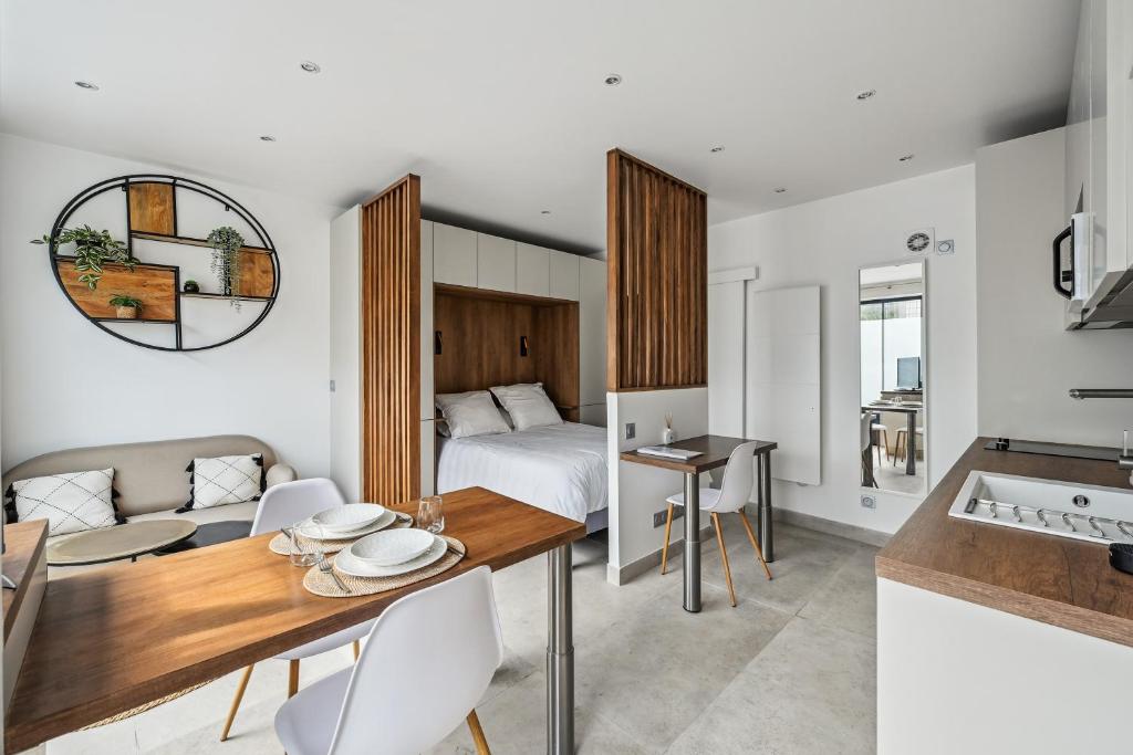 une chambre avec un lit, une table et des chaises dans l'établissement Le Studio Scandinave - 25min de Paris, à Courbevoie