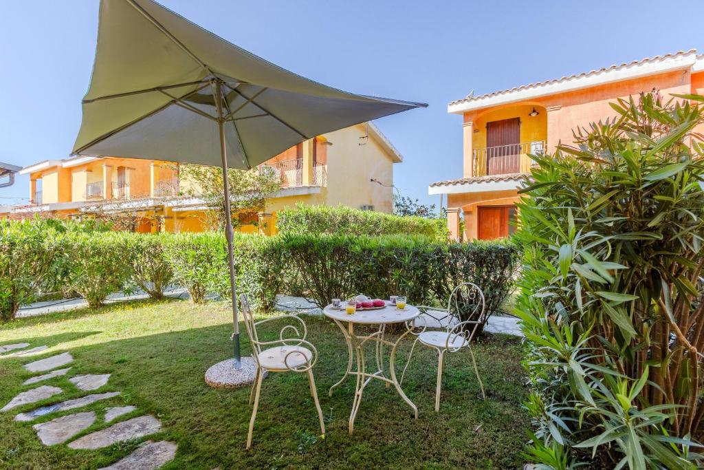 a table and chairs with an umbrella in a yard at Villa Emerald private compound swimming pool in SantʼAnna Arresi
