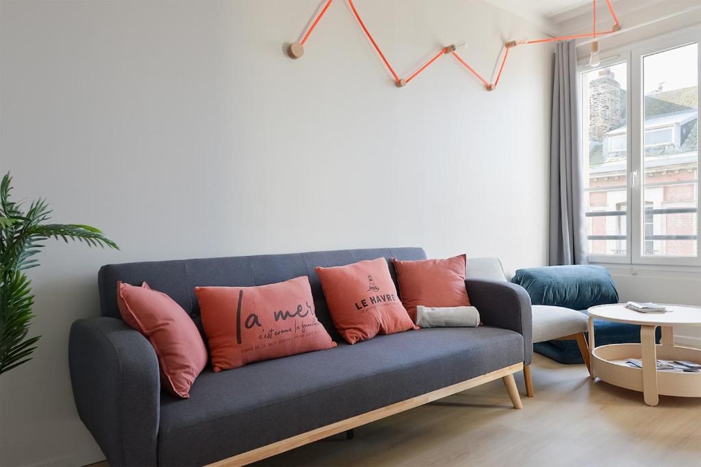 - un salon avec un canapé bleu et des oreillers roses dans l'établissement Le Grand Large Vue mer, au Havre