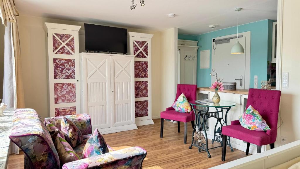 a living room with pink chairs and a table at 6-401, Extravagante Strandwohnung, Art Nouveau meets französischen Landhausstil! 1Zimmer in Westerland (Sylt)