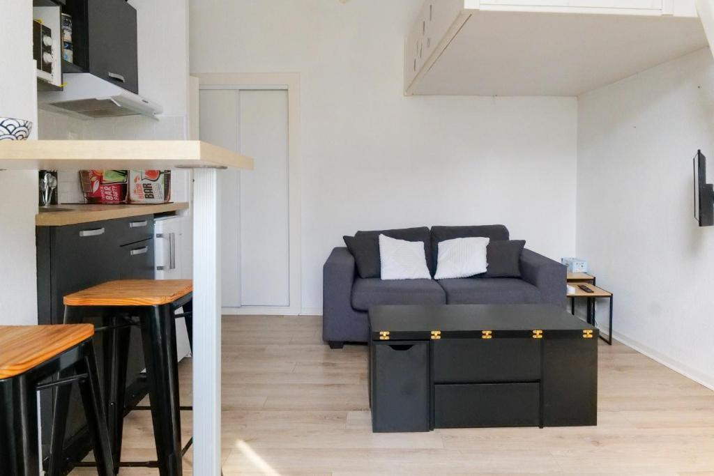 un salon avec un canapé bleu dans une cuisine dans l'établissement Studio douillet entre ville et océan - Etage 1 - Proche toutes commodités, à Les Sables-dʼOlonne