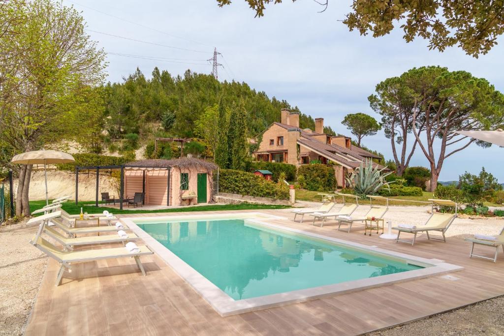 a swimming pool with chairs and a house at VILLA LIA 10, Emma Villas in Ascoli Piceno