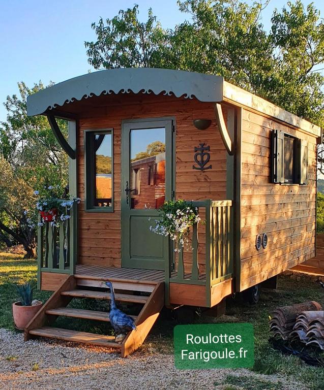 une petite maison en bois avec un coq debout à l'extérieur dans l'établissement Roulotte domaine Farigoule, à Baron