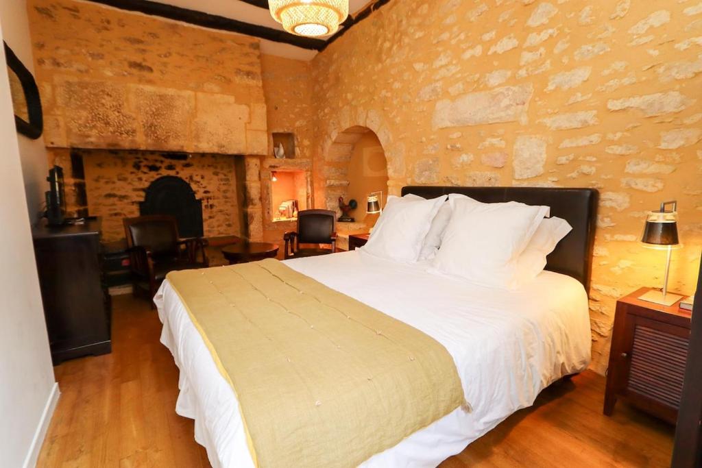 une chambre avec un grand lit et un mur en pierre dans l'établissement Le Coq de Landry, à Sarlat-la-Canéda