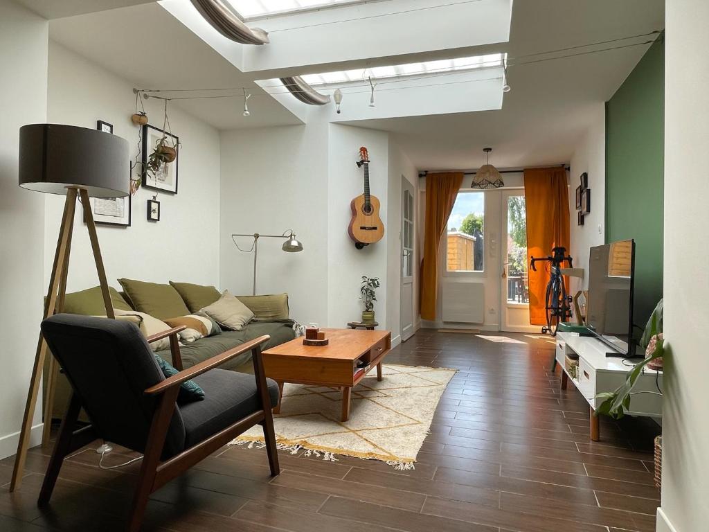 - un salon avec un canapé et une guitare sur le mur dans l'établissement Chambre chez l habitant avec jardin près de Lille, à Pérenchies
