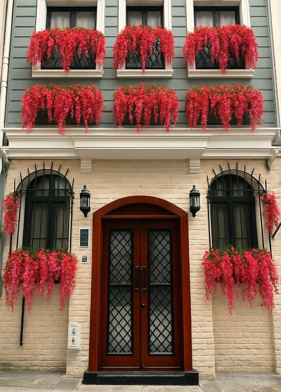 a building with red flowers in windows and a door at THE MUA LUXURY HOMEs in Istanbul