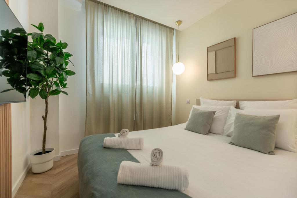 - une chambre avec un grand lit blanc et une plante en pot dans l'établissement Le Lusso - L'élégance au cœur de Bergerac, à Bergerac