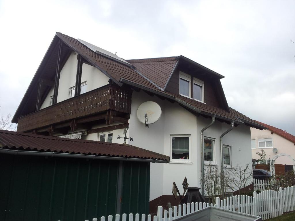 ein weißes Haus mit einem braunen Dach und einem Zaun in der Unterkunft FERIENHAUS FISCHER in Zweibrücken