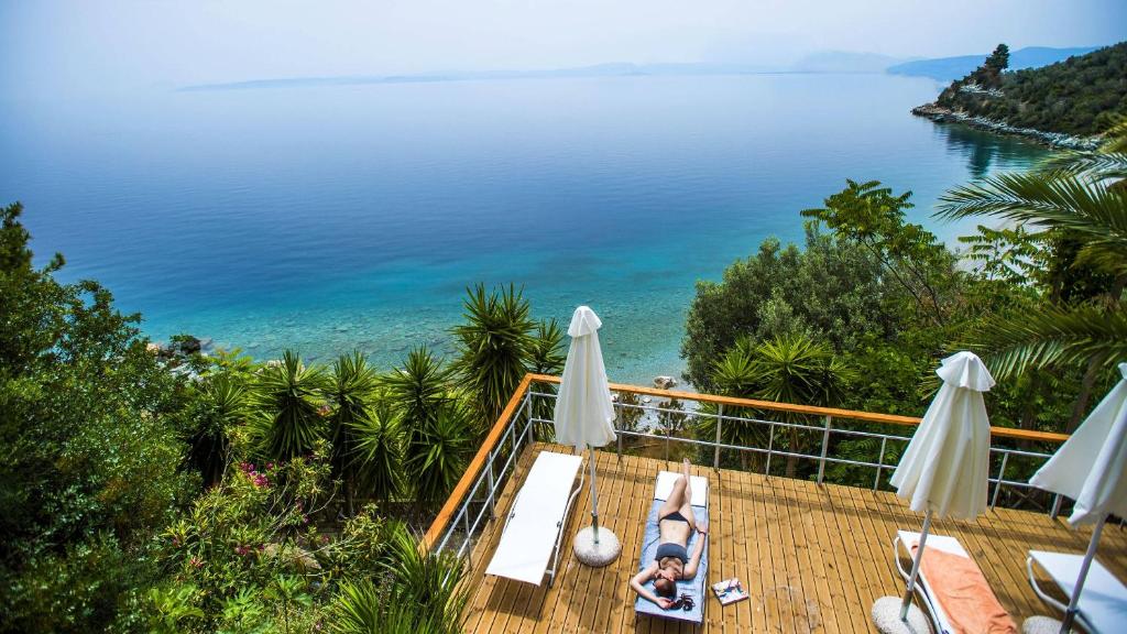 a woman laying on a deck with a view of the ocean at Penelope's Blue Sea Front Residenses in Ilia