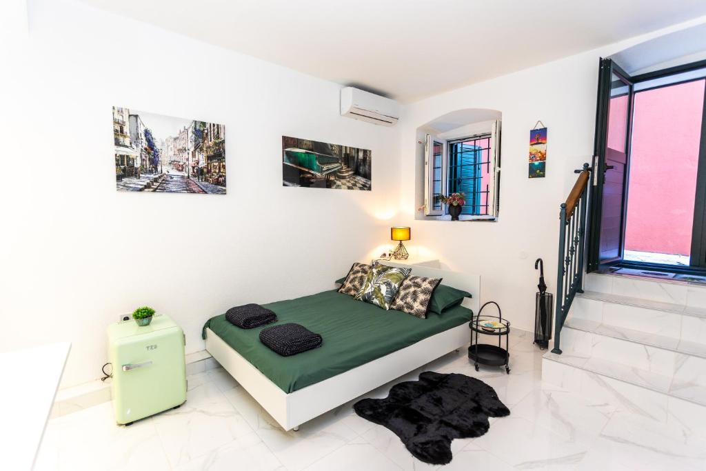 Un dormitorio con una cama verde en una habitación blanca en The Little Prince apartman Herceg Novi, en Herceg-Novi