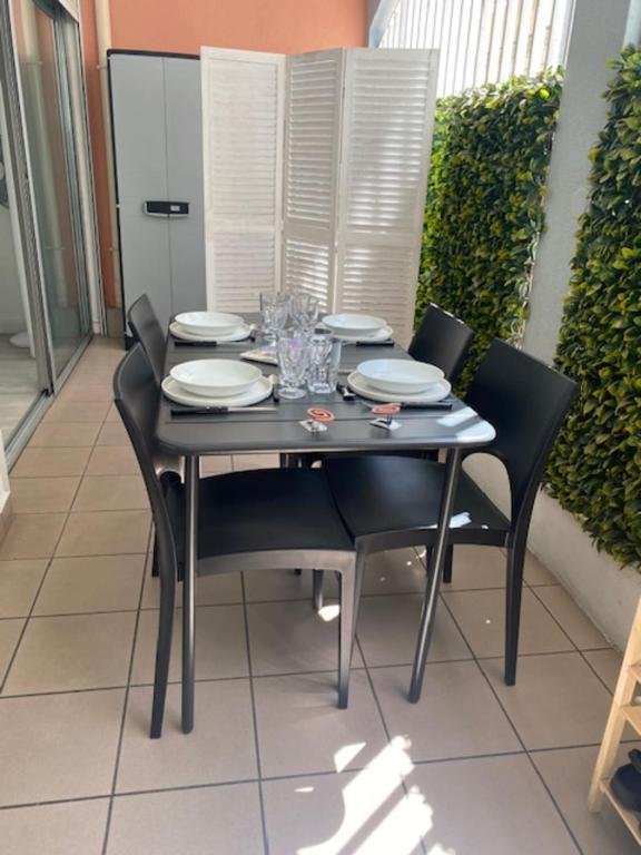 une table noire avec des chaises et des assiettes noires dans l'établissement Apartment sea side, à Antibes