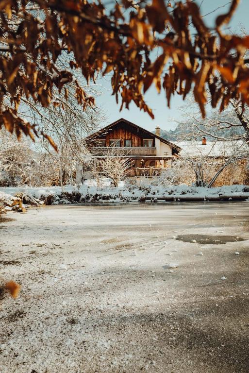 a log cabin in the snow with a building at Haus am Weiher in Schwangau