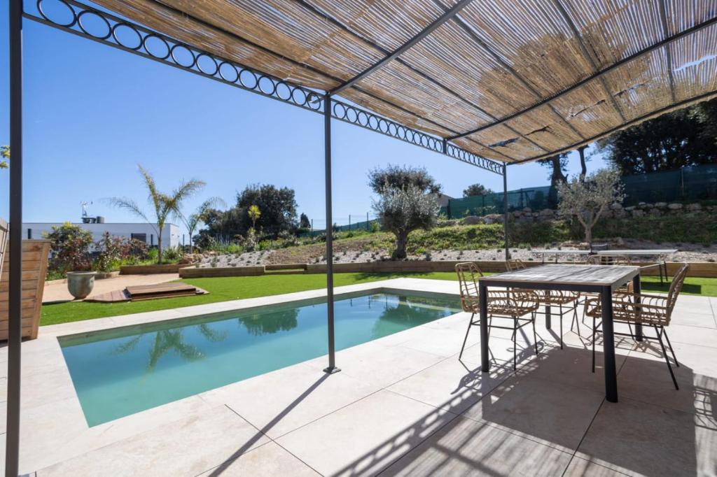 un patio avec une table et des chaises et une piscine dans l'établissement Villa Capucine - Modern Villa, à Antibes