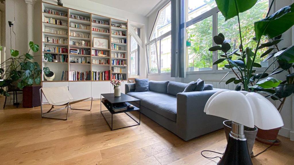 un salon avec un canapé et une étagère dans l'établissement Quiet and bright loft, à Paris