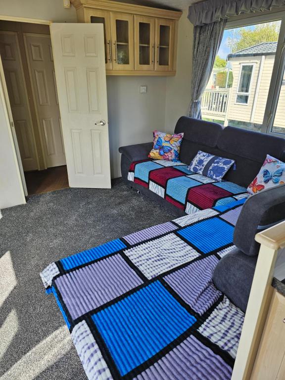a living room with a couch and colorful blankets at Sandys Secret Corner Centrally Heated Southview SKEGNESS in Winthorpe