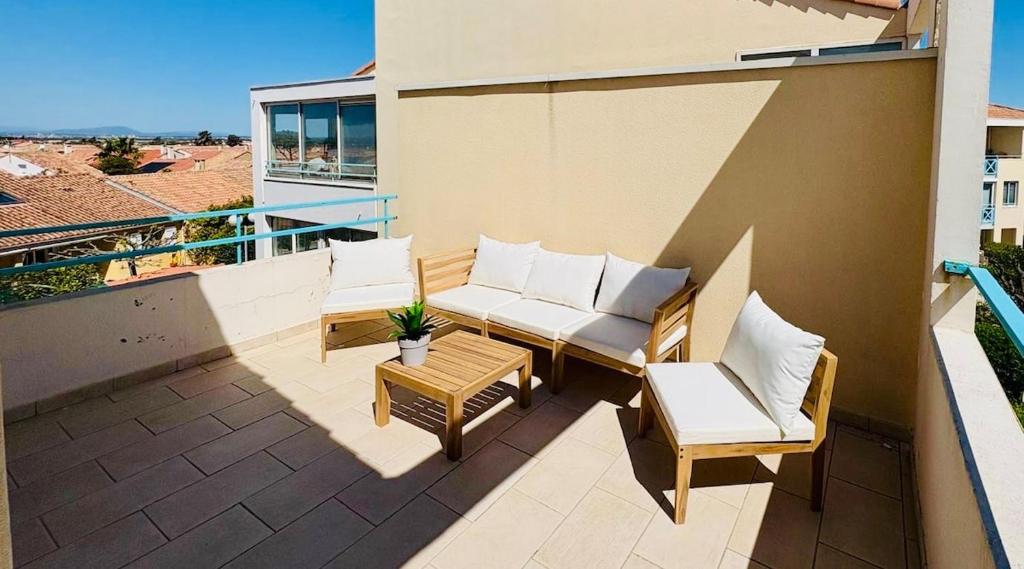 un patio avec deux chaises et une table sur un balcon dans l'établissement Appartement climatisé, double vue mer et Pic, accès mer et Parking privatif, à Palavas-les-Flots