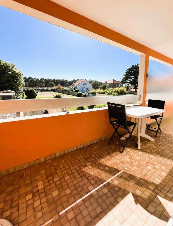 une terrasse avec une table et des chaises ainsi qu'une grande fenêtre. dans l'établissement Plage et centre à 100m avec balcon et parking privé 4 pers, à Saint-Brévin-lʼOcéan