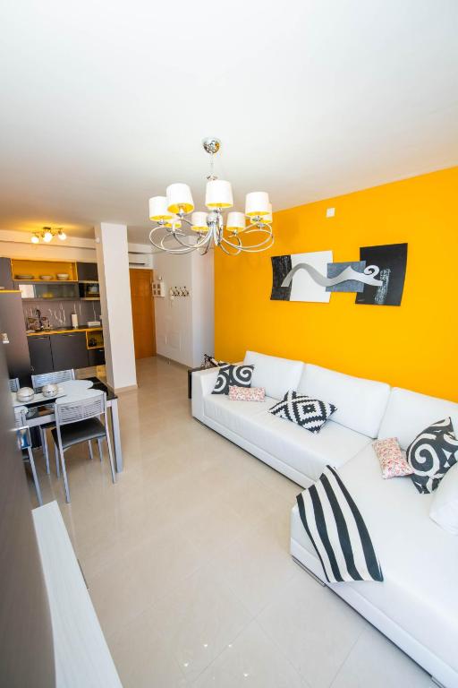 a living room with two white couches and a yellow wall at La Rosa in Gran Tarajal