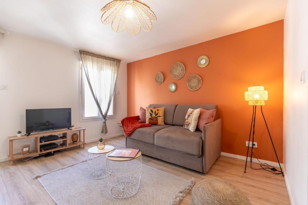 a living room with a couch and a tv at Le Corallo - T2 cosy et moderne en hyper-centre in Bergerac