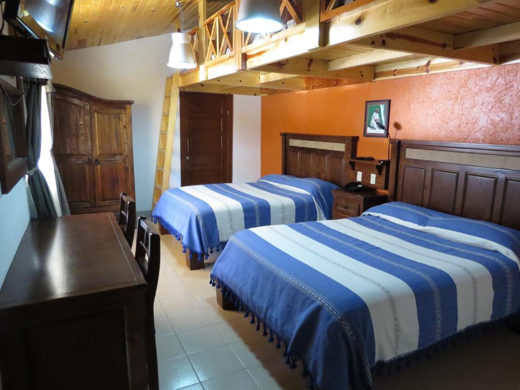 a hotel room with three beds and a table at Hotel Ecológico Temazcal in Creel