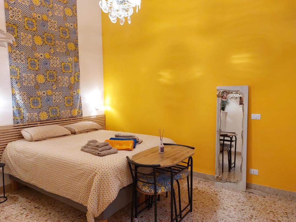 a bedroom with a bed with a table and a yellow wall at Suite La TERRAZZA ILLUMINATA in Trapani