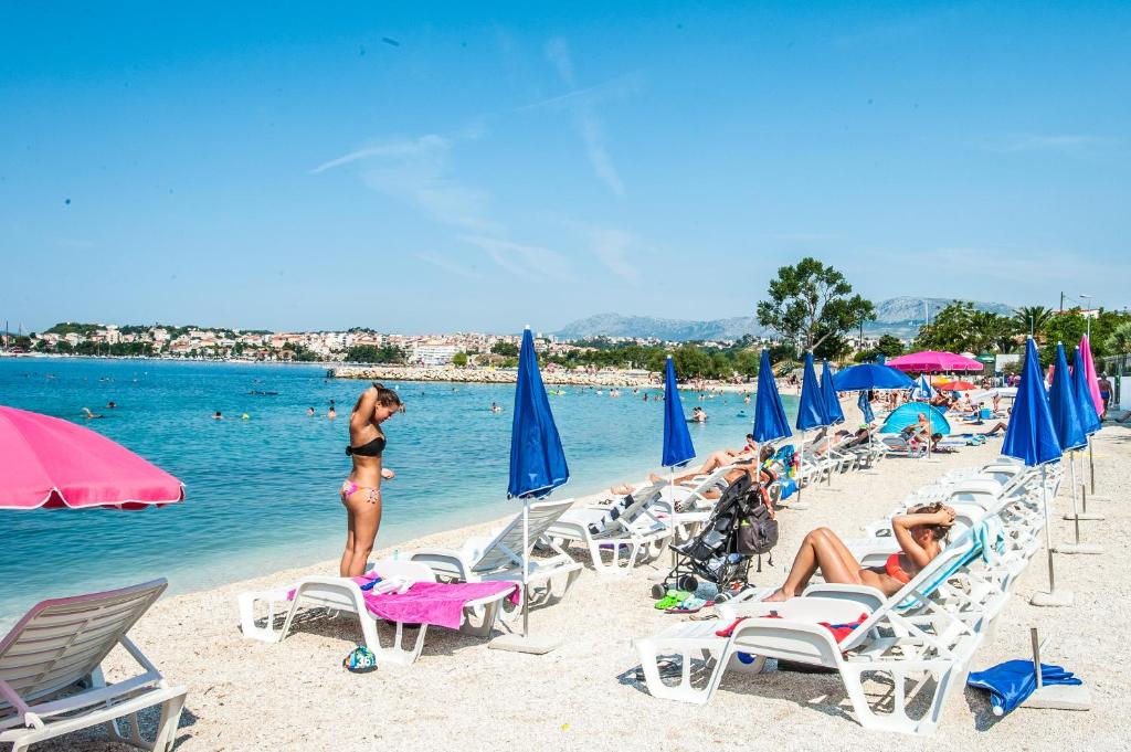a group of people on a beach with chairs and umbrellas at Dadule Apartments in Strožanac