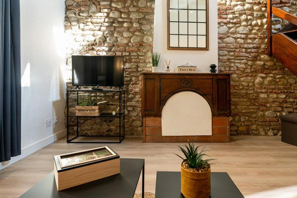 un salon avec une télévision et un mur en pierre dans l'établissement Atlas - Nexus, à Perpignan