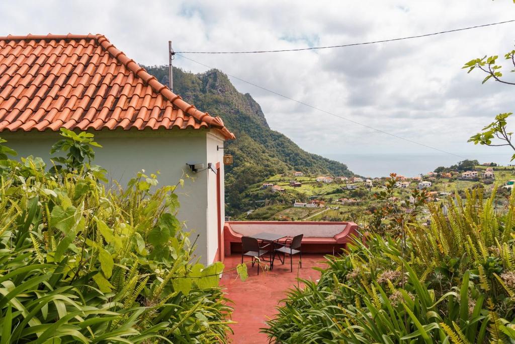 una casa con un tetto di tegole rosse, un tavolo e delle sedie di GuestReady – Rustic Charm in Peaceful Madeira a Porto da Cruz