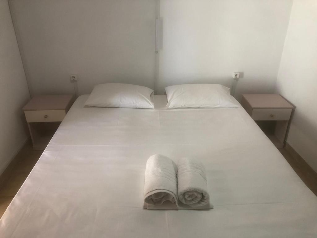 a white bed with two pillows and towels on it at Barreira Beachfront Room 5 in Kalamata