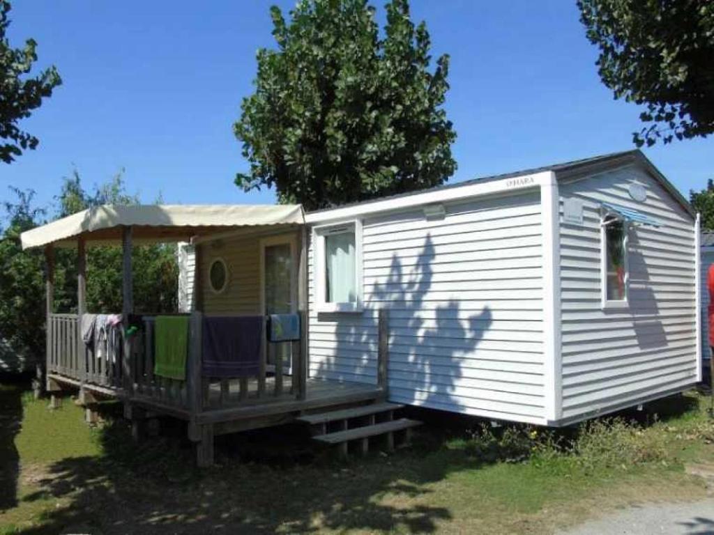 Ce mobile home blanc dispose d'une terrasse couverte et d'un auvent. dans l'établissement Camping 4 étoiles - Parc aquatique - ccbahfb, à Saint-Hilaire-de-Riez