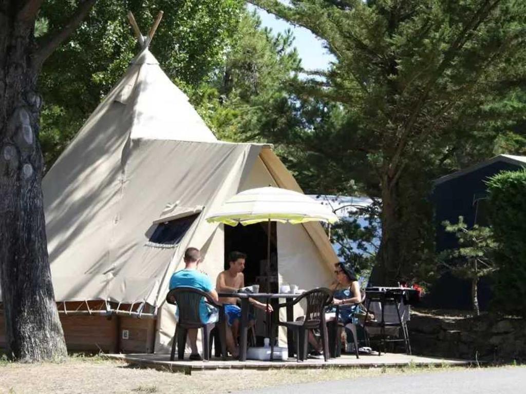 un groupe de personnes assises à une table devant une tente dans l'établissement Camping 4 étoiles - Parc aquatique - ccbahge, à Saint-Hilaire-de-Riez