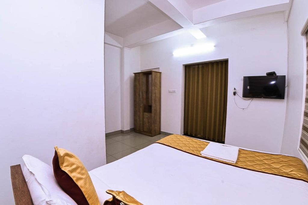 a bedroom with a bed and a tv on the wall at Nirupama,Hotel Aluva 700 Mtr From Aluva Railway Station in Alwaye