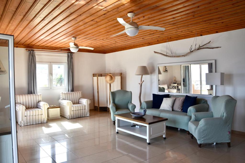 a living room with a couch and chairs and a ceiling at Deep Blue Apartments in Karpathos