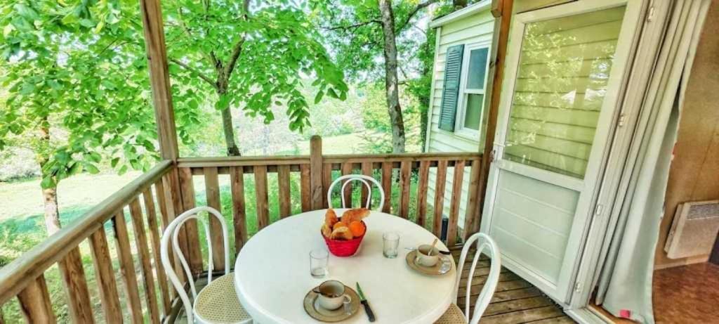 einen weißen Tisch und Stühle auf einer Veranda in der Unterkunft Camping 3 étoiles - Parc aquatique - ccbbeec in Beaumont-du-Périgord