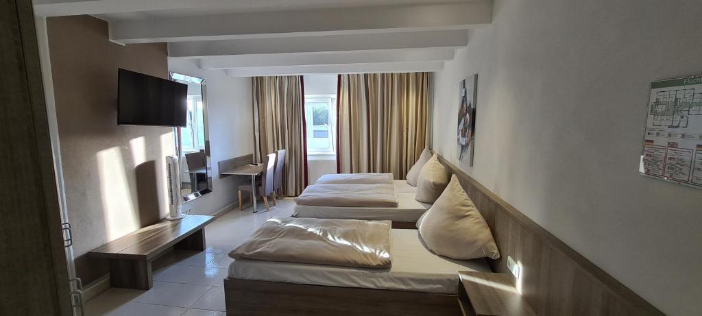 Una habitación de hotel con dos camas y un televisor. en Bach Hotel, en Porta Westfalica
