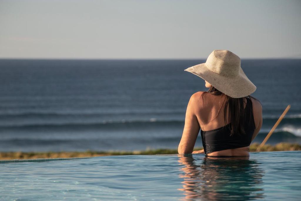 a woman in a hat sitting in the water at Hotel Verde Mar & SPA in Ribeira Grande