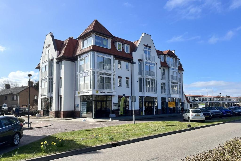 Un gran edificio blanco con coches aparcados en un estacionamiento. en 33 at Sea 305, en Cadzand