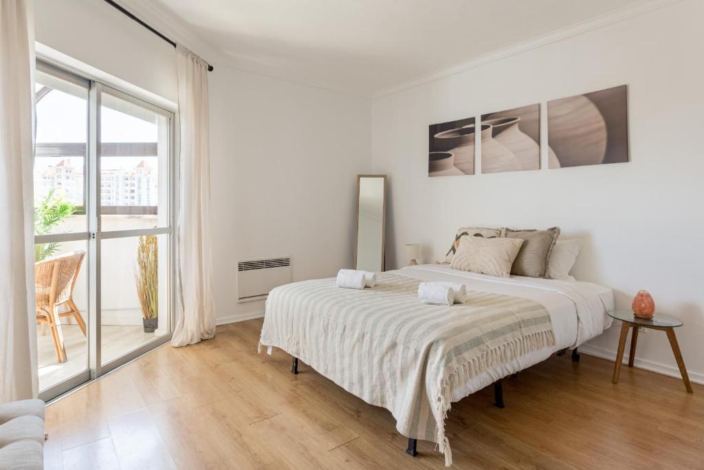 a white bedroom with a bed and a large window at Cascais Ocean View by Homing in Cascais