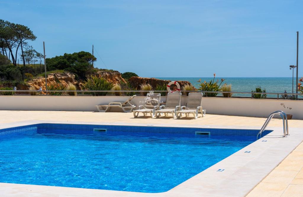 a swimming pool with a table and chairs next to the ocean at Apartamento Varandas do Mar in Olhos de Água