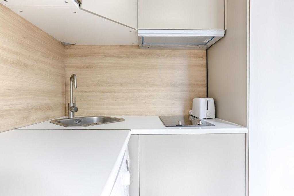 une petite cuisine avec deux lavabos et un four micro-ondes dans l'établissement Cozy Studio on Mobility Lease, à Boulogne-Billancourt