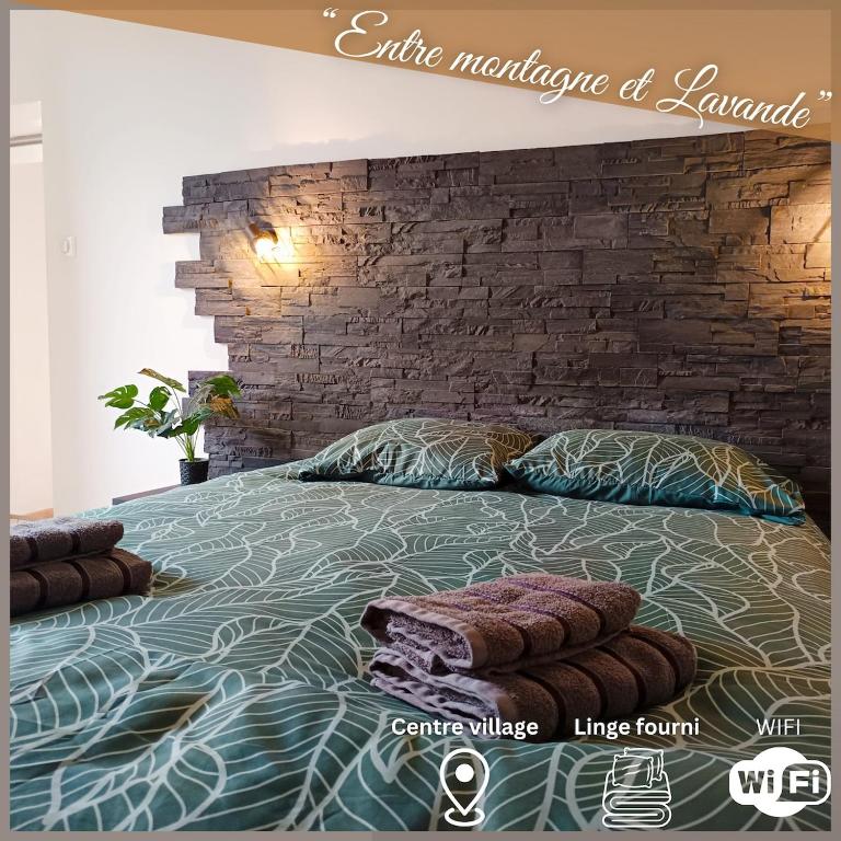 une chambre avec un grand lit avec un mur de briques dans l'établissement Entre montagne et lavande - Maison Provençale, à Saint-Étienne-les-Orgues