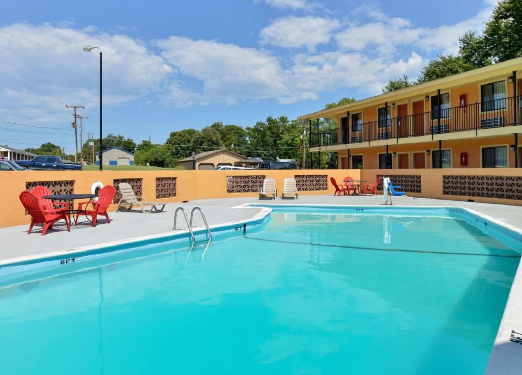 une piscine dans un hôtel avec des chaises rouges et un bâtiment dans l'établissement Americas Best Value Inn Ponca City, à Ponca City