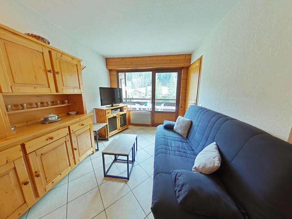 un salon avec un canapé bleu et une cuisine dans l'établissement Appartement cosy 2 pièces, 6 couchages, animaux acceptés, casier à skis, centre proche - FR-1-241-193, au Grand-Bornand