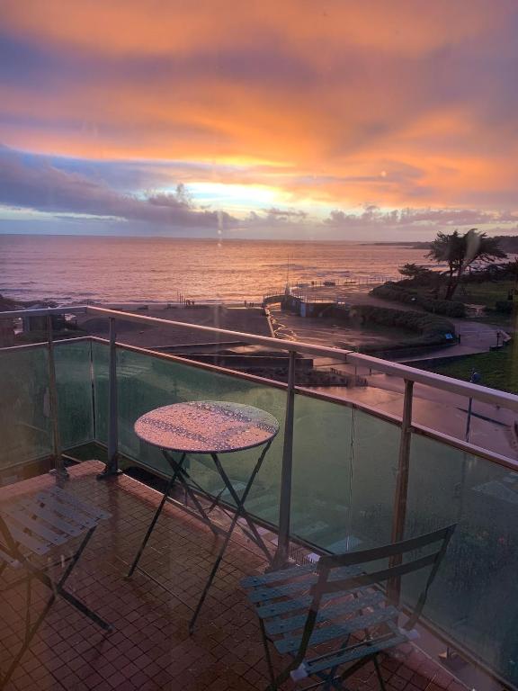 une table et des chaises sur un balcon avec l'océan dans l'établissement Appartement, à Préfailles