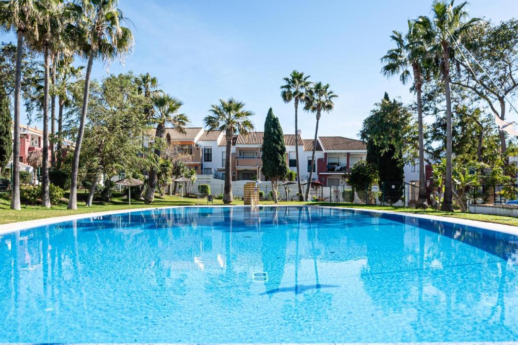 a large blue swimming pool with palm trees at aldea 3 4 1ºB in Novo Sancti Petri