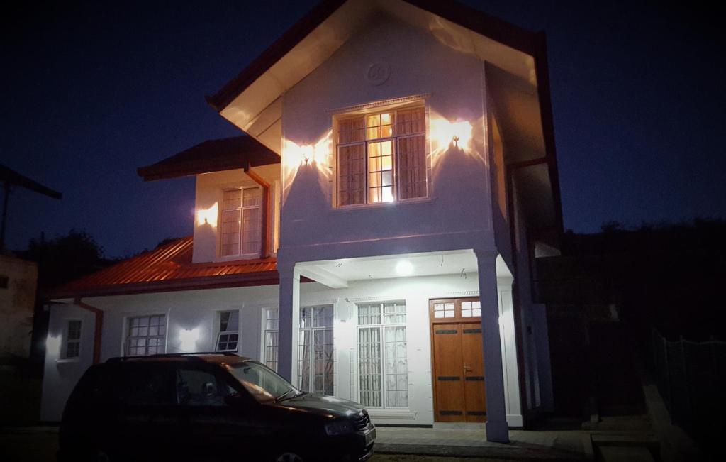 ein Haus mit einem Auto, das nachts davor geparkt ist in der Unterkunft Thuring's Holiday Bungalow in Nuwara Eliya