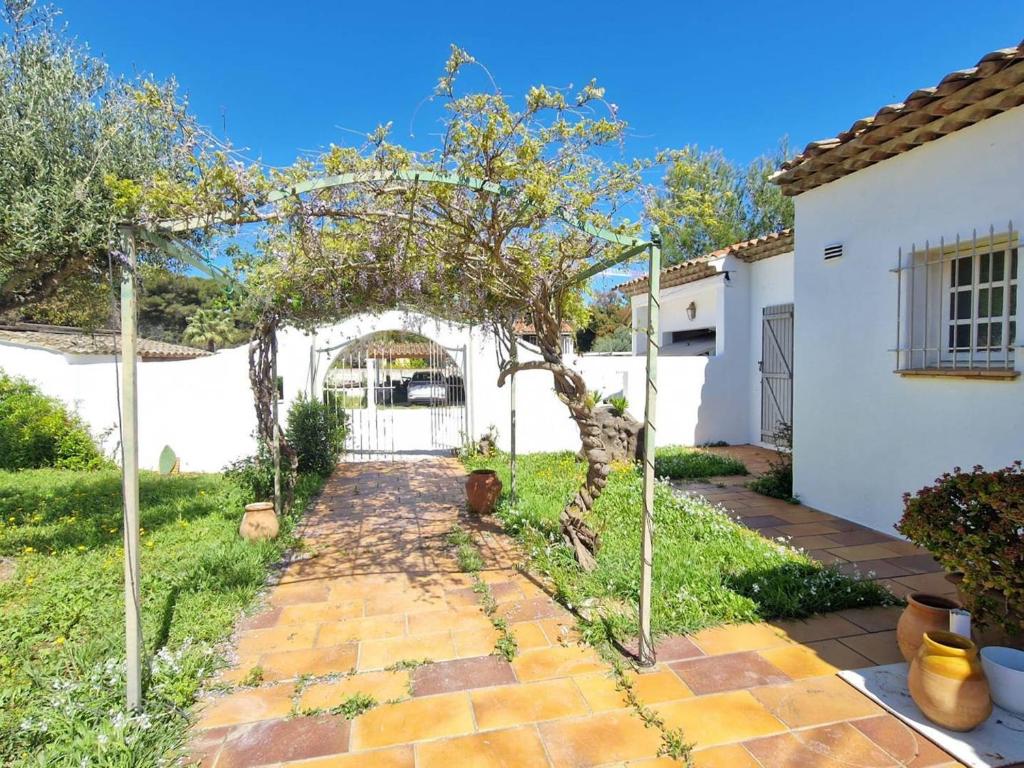un jardin avec un chemin menant à une maison blanche dans l'établissement Maison climatisée avec grand jardin, proche plage et commerces - FR-1-610-102, à Bormes-les-Mimosas