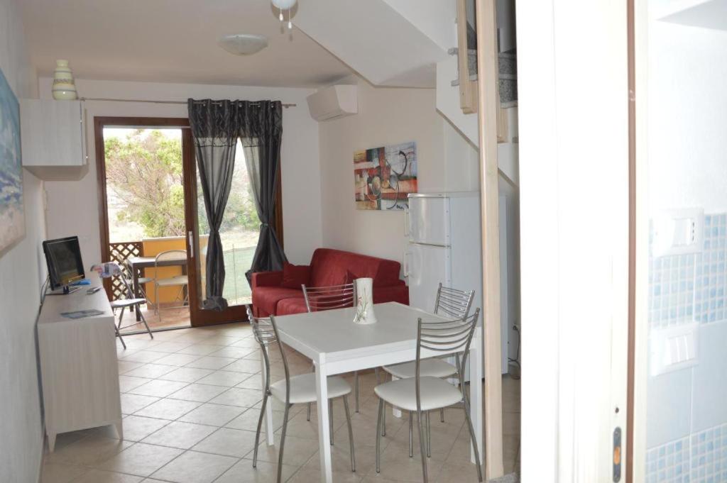 a kitchen and living room with a white table and chairs at Appartamento su due piani con vista mare in Castelsardo