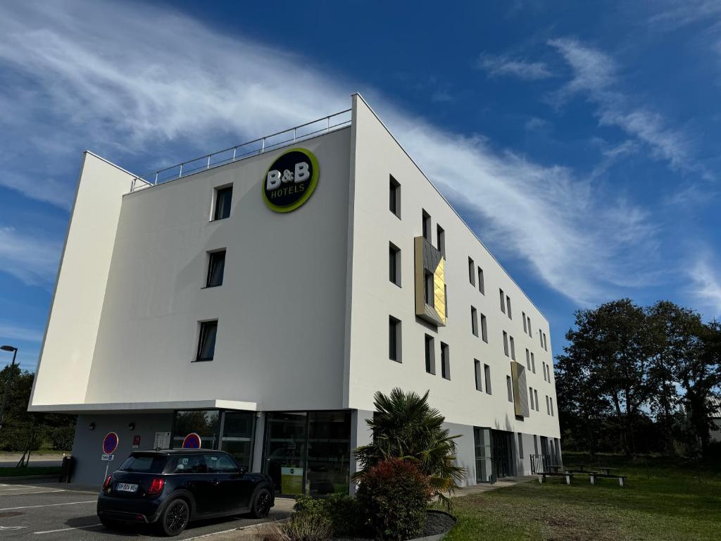 a white building with a car parked in front of it at B&B HOTEL Nantes Savenay in Savenay