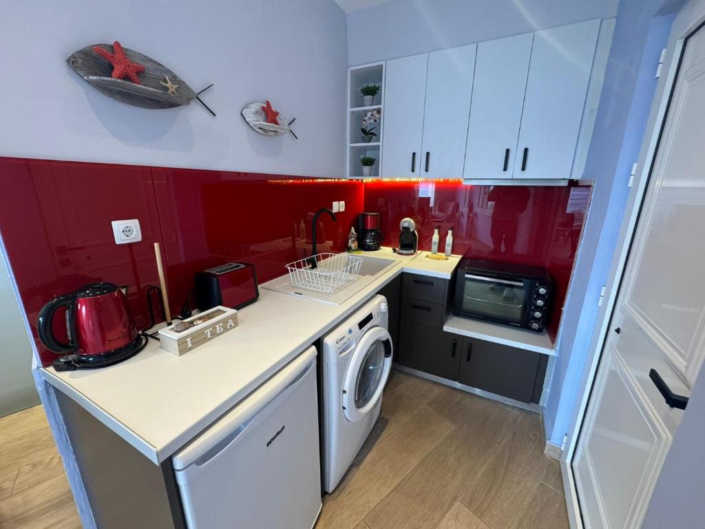 a kitchen with red and white cabinets and a washing machine at Eleftherias Suites - Near Beach Apartments in Marathi
